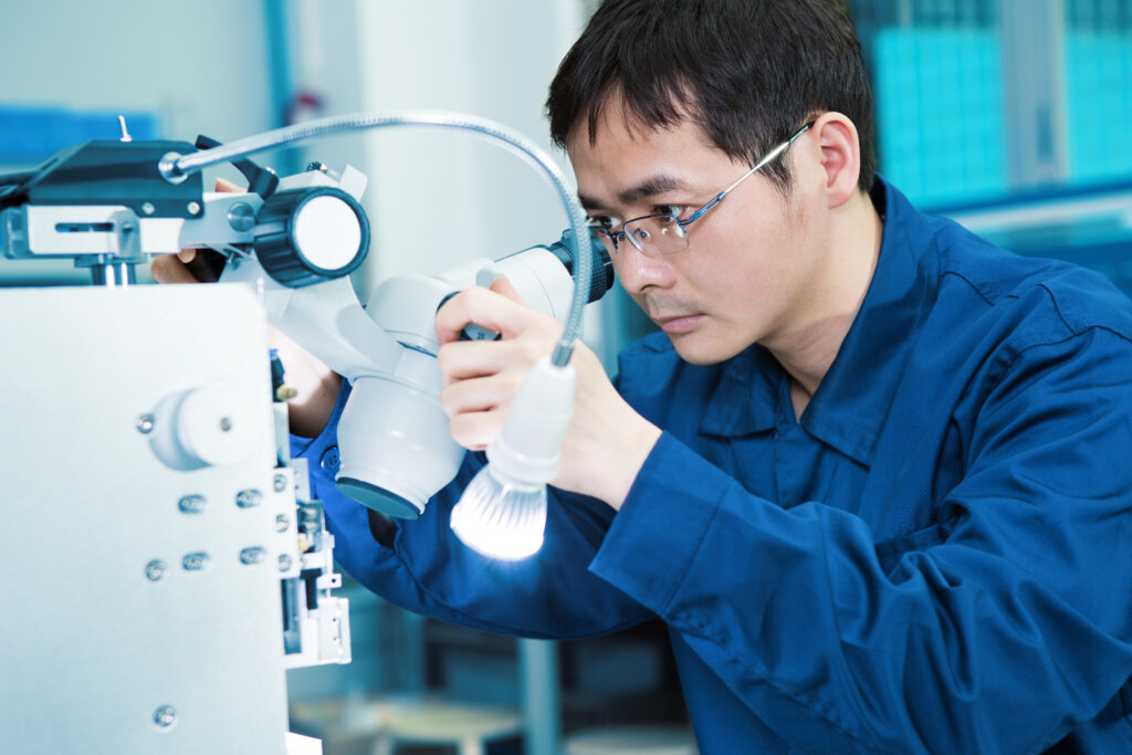 A male scientist working on an instrument in a lab setting.