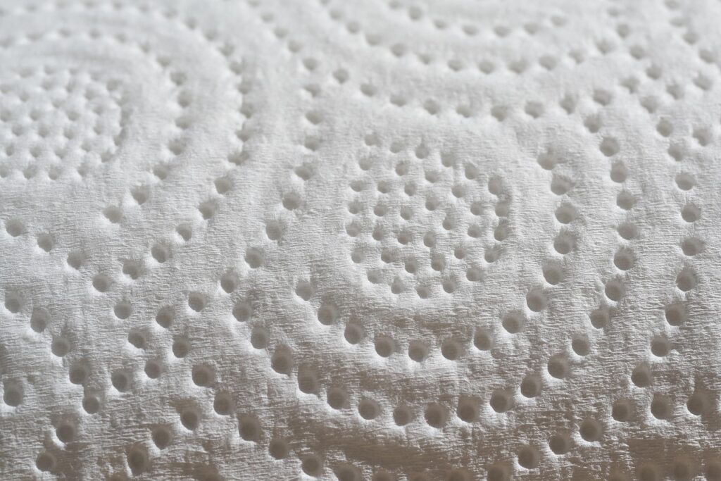 The image shows a close-up of a white material with a textured, dimpled surface arranged in concentric patterns. This visual closely resembles the microstructure of a porous ceramic surface or a laboratory simulation of ceramic porosity. The uniform depressions indicate a controlled manufacturing or testing process, possibly used to assess porosity levels, mechanical strength, or fluid absorption characteristics in ceramic materials.