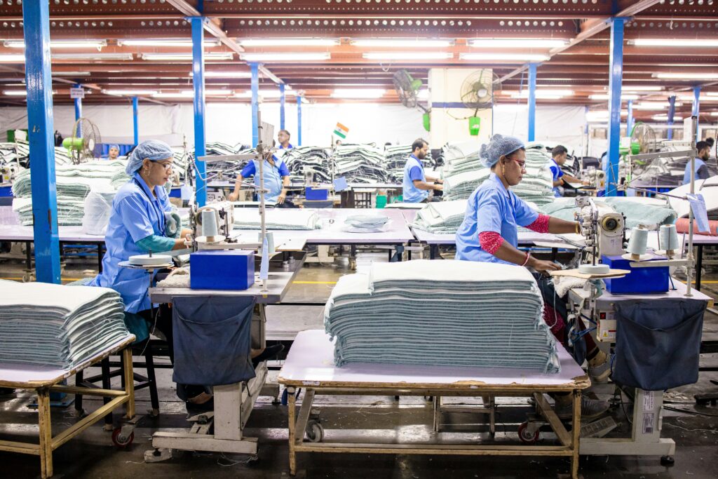 Women in PPE sewing fabric in an industry workshop setting.