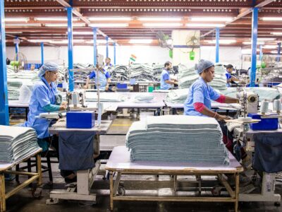 Women in PPE sewing fabric in an industry workshop setting.