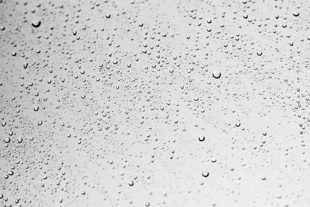 The image shows a close-up view of a surface covered with numerous small water droplets, likely condensation on glass or a glazed ceramic surface. The varying sizes and distribution of the droplets suggest testing or observation of surface wettability, hydrophobicity, or coating performance. This type of visual is commonly used in surface energy analysis or anti-fog/anti-wetting studies for glass and ceramic materials.