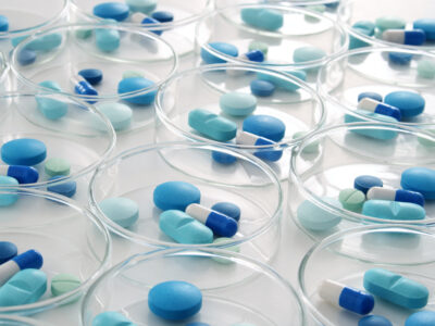 Clusters of blue pills arranged in a series of petridishes.