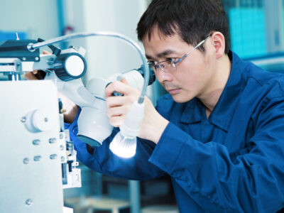A male scientist working on an instrument in a lab setting.