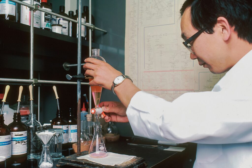 A male researcher perfroms titration in a chemistry lab set-up.