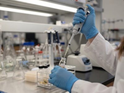 Gloved lab technician preparing a food sample with a pipette for nutritional analysis testing in a laboratory