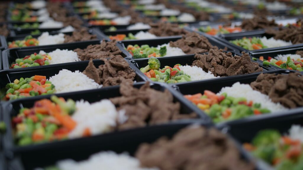 Boxed lunches with rice, vegetables, and meat ready to be packed.